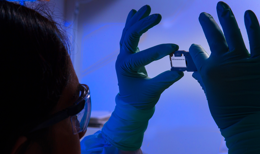 This photograph depicted an Enteric Diseases Laboratory Branch (EDLB) public health scientist, holding up a glass slide used for a run on a sequencing machine. Image courtesy CDC